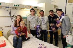Der Besuch im St. Anna Kinderspital hinterließ auch heuer wieder strahlende Gesichter. V.l.: David de Paula, Ronivaldo, Marios Pechlivanis und Marco Meilinger mit einem kleinem Paienten. Foto: FK Austria Wien