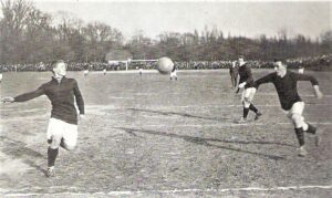 Spielszene aus der allerersten Meisterschafts-Saison in Österreich vom Sonntag, 3. März 1912: Auf dem WAC-Platz in der Rustenschacherallee im Wiener Prater, den es im übrigen heute noch gibt, traf der Wiener AC (kurz WAC und in keinster Weise mit dem Wolfsberger AC zu verwechseln) auf den Wiener Association FC (kurz WAF). Der WAC gewann mit 3 : 1. Schiedsrichter dieser Partie war übrigens Hugo Meisl (im Hintergrund, Herr im Anzug), der heute noch als der Vater des Österreichischen Wunderteams https://www.oepb.at/allerlei/die-geschichte-eines-bildes.html gilt. Im Bild links der WAF-Spieler Karl Tekusch, der zur damaligen Zeit als einer der besten Centerhalfs (Mittelläufer) in der Monarchie galt.  Foto: oepb