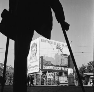 Ein Bild, das bis in die späten 1980er Jahre hinein keine Seltenheit war: Kriegsversehrte nämlich. Hier beim Betrachten eines Wahlplakats der ÖVP zu den Nationalratswahlen in Wien 1949. Foto: Okamoto / ÖNB