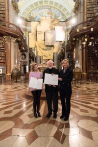 Anne-Sophie Mutter (links), John Williams und Generaldirektorin Dr. Johanna Rachinger im Prunksaal der Österreichischen Nationalbibliothek. Foto: © Terry Linke / Deutsche Grammophon 