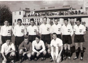 Die Österreichische Nationalbank hatte den ehemaligen HSV-Platz in der Heiligenstädter Lände erworben und zu einer Sportanlage umgestaltet, die nach jeder Richtung hin als ideal und mustergültig zu bezeichnen ist: Fußballfeld, Laufbahn, Kabinen, Klubheim und Publikumsanlage. Zur feierlichen Eröffnung trat am 17. Juli 1954 der SK RAPID Wien an. Robert Dienst (rechts vorne hockend mit Spielwimpel) kickte eine Halbzeit für den einen Arbeitgeber, die Nationalbank, und die andere Halbzeit für RAPID. Endstand 8 : 0 für Grün-Weiß, zweifacher Torschütze Robert Dienst. Foto: © oepb